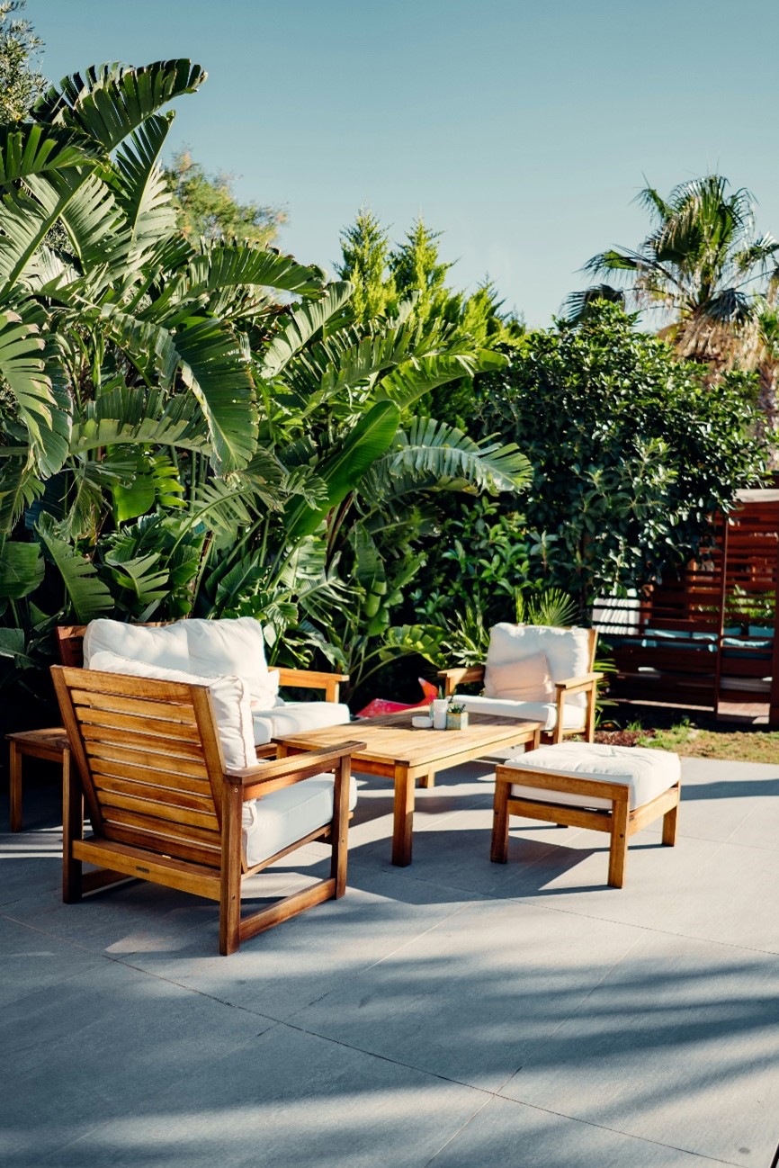 Salon de jardin bois, coussins clairs, sur une terrasse ombragée