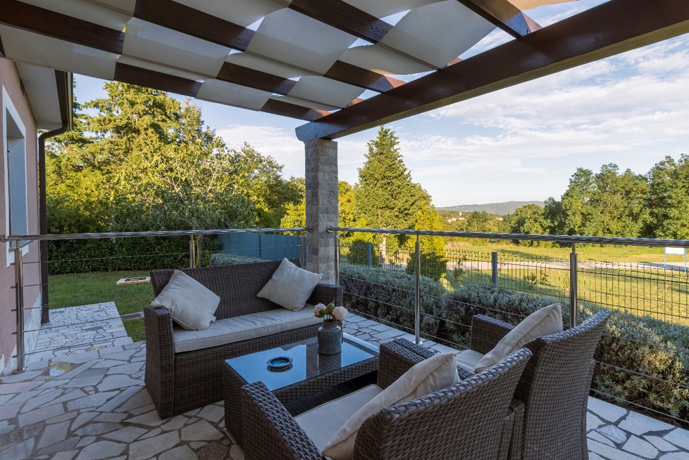 salon de jardin en résine tressée composé d’un canapé 2 places, 2 fauteuils et une table sur une terrasse.