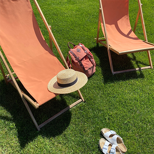 2 transats bois et orange, dans jardin sur l'herbe