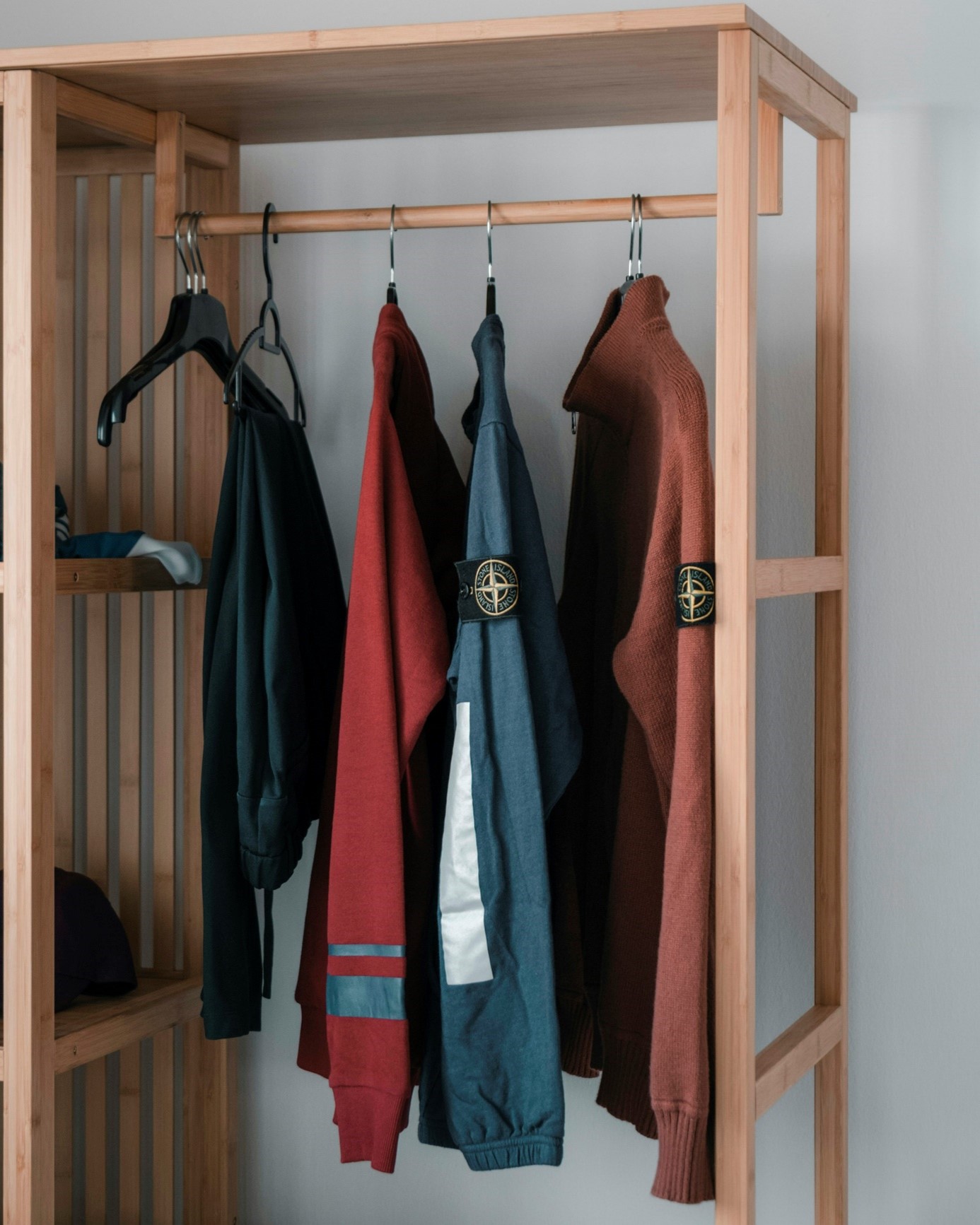 Un dressing couleur bois avec des vêtements accrochés dans la penderie