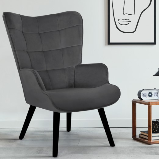 Un fauteuil en velours gris de style scandinave avec quatre pieds bois noir