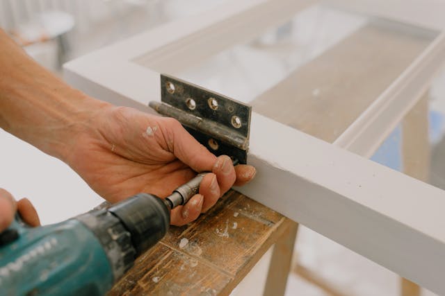 une visseuse et une fixation pendant un bricolage sur une porte vitrée